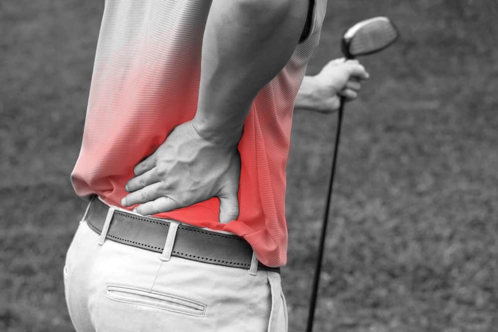 Man gripping lower back on golf course